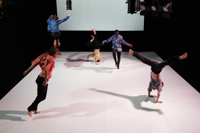 Five dancers moving fast on a stage