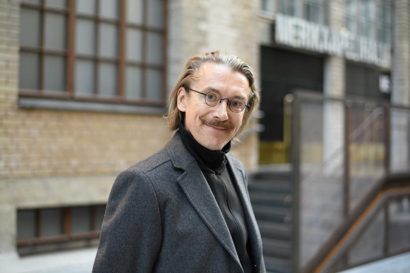 Jyrki Karttunen smiling in front of a grey building.