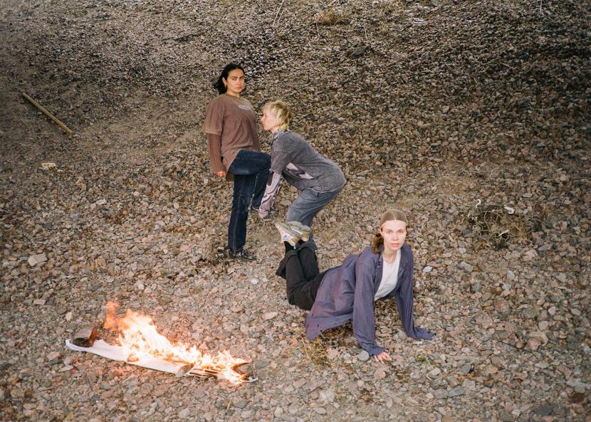 Photo: Adele Hyry PR photo.There are three people in the photo. The ground is made of pebbles.