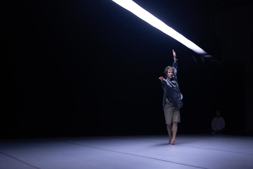 Esityskuva, jossa Elias Girod tumman huoneen takaosassa symmetrisessä asennossa, huonetta halkaisee viivamainen valo.