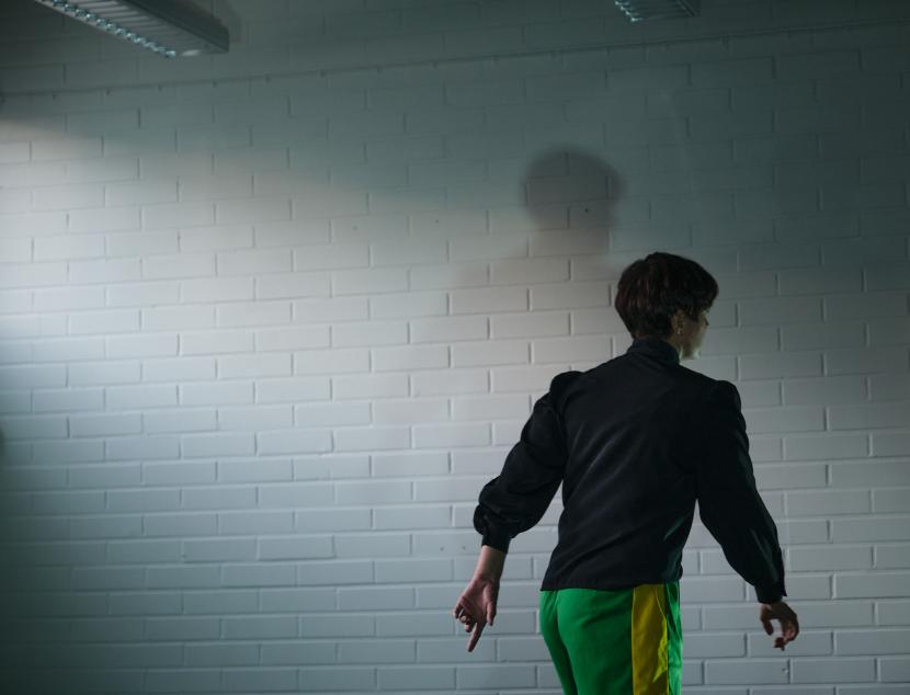 Dancer facing the wall in the dark room.