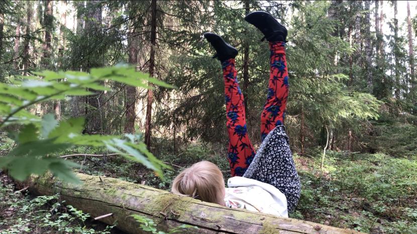 Sofia Simola on her back in the woods. The feet up in the air.